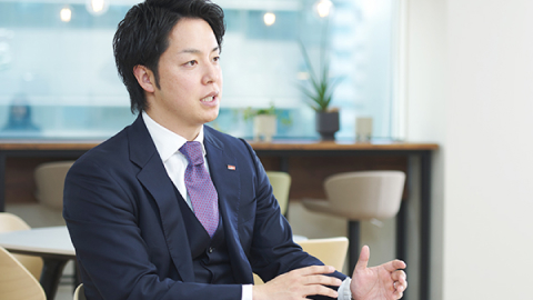 スーツを着た男性が身振り手振りを交えて説明する様子